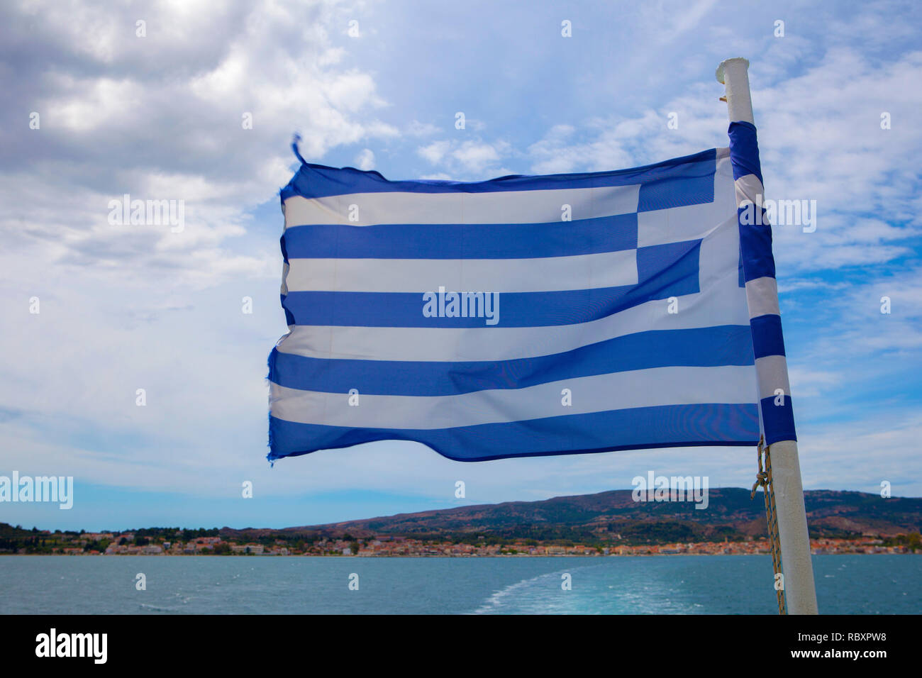 Greek flag blowing in the wind on the back of a ferry, Kefalonia. Stock Photo