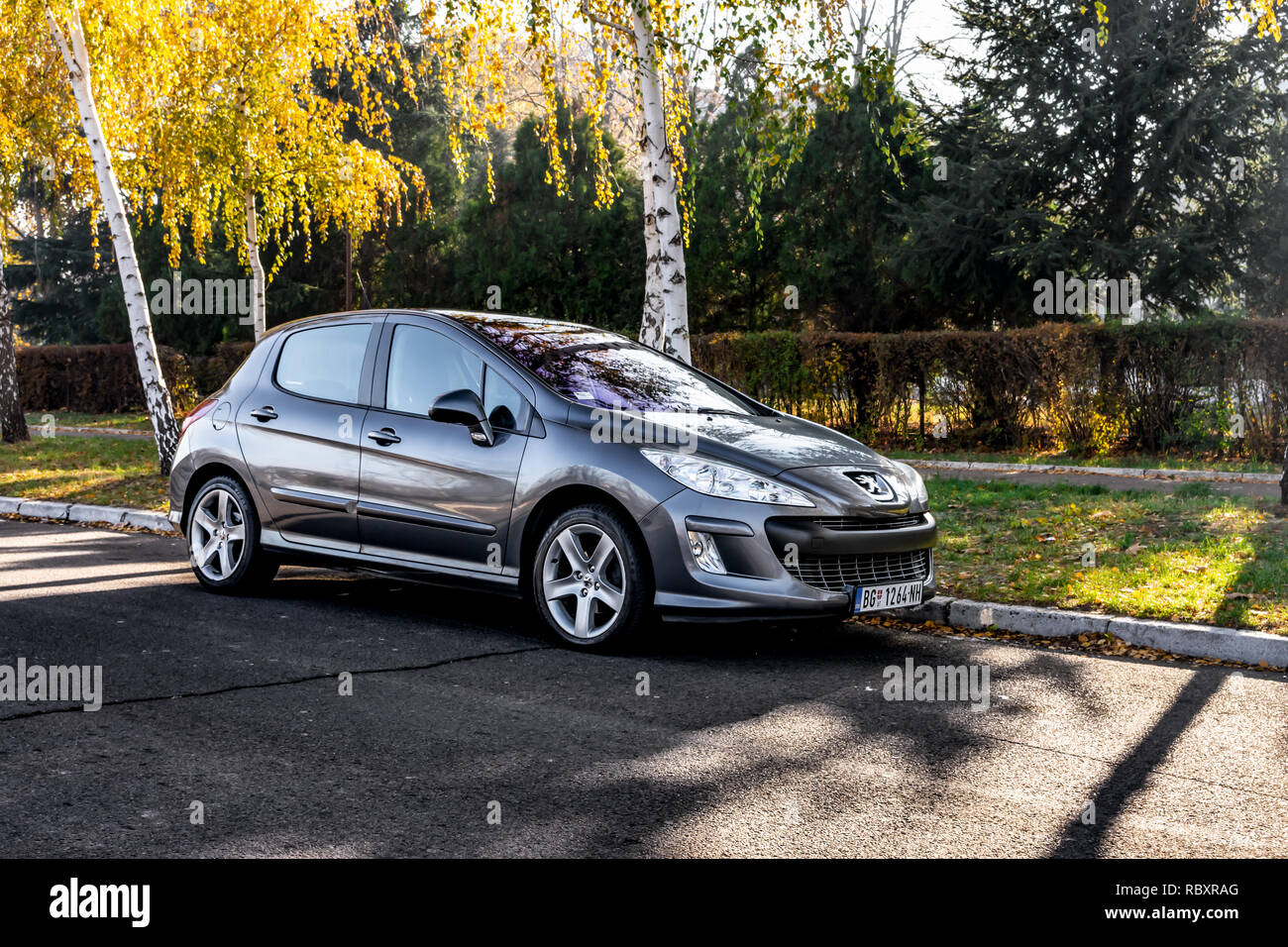 Belgrade, Serbia - 11.21.2018 / Peugeot 308 2.0 hdi, with gray color, parked on the street, near tree with yellow leaves, big alloy wheels. Stock Photo