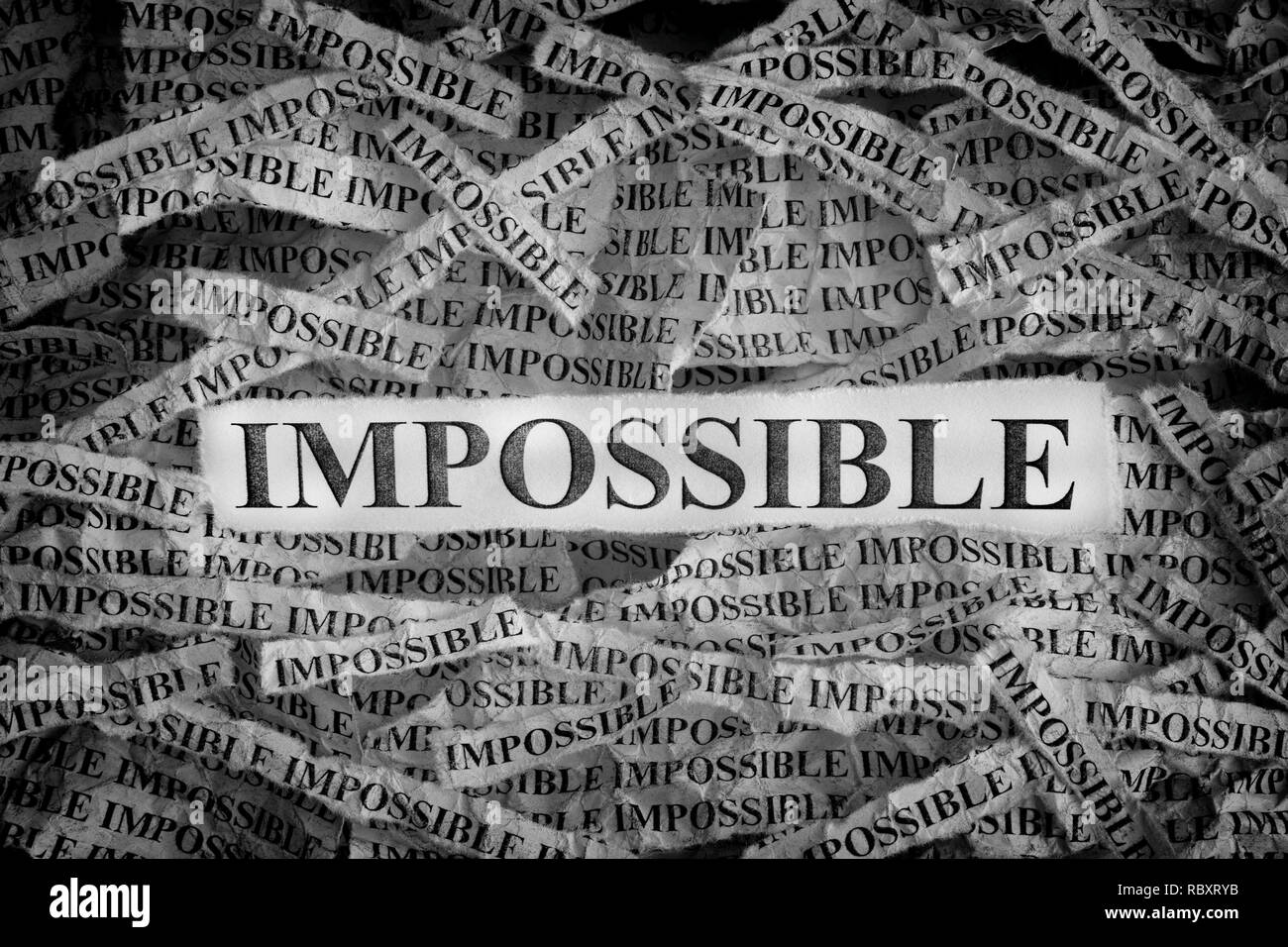 Impossible. Torn pieces of paper with the words Impossible. Concept image. Black and White. Close up. Stock Photo