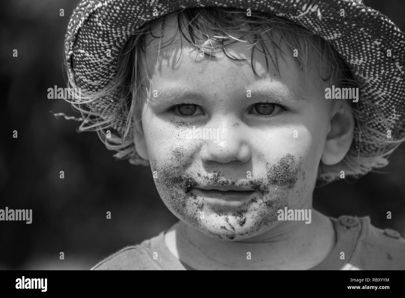 A B&W portrait of a young boy wearing a rugged hat Stock Photo