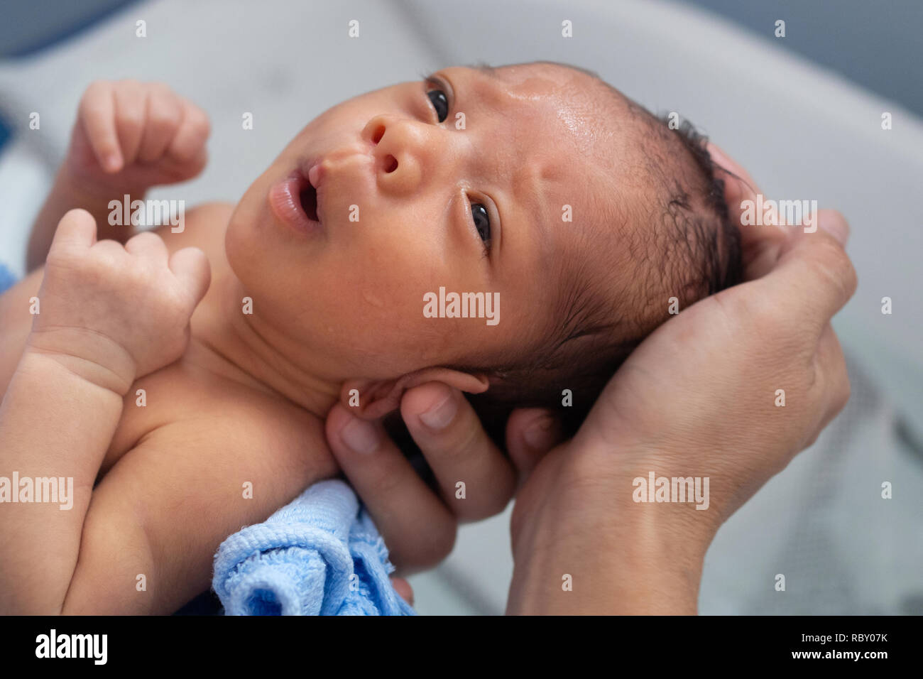 happy asian baby boy feeling cold to taking bath at the first time of life. mother holding and bathing newborn baby in the morning. baby lifestyle con Stock Photo