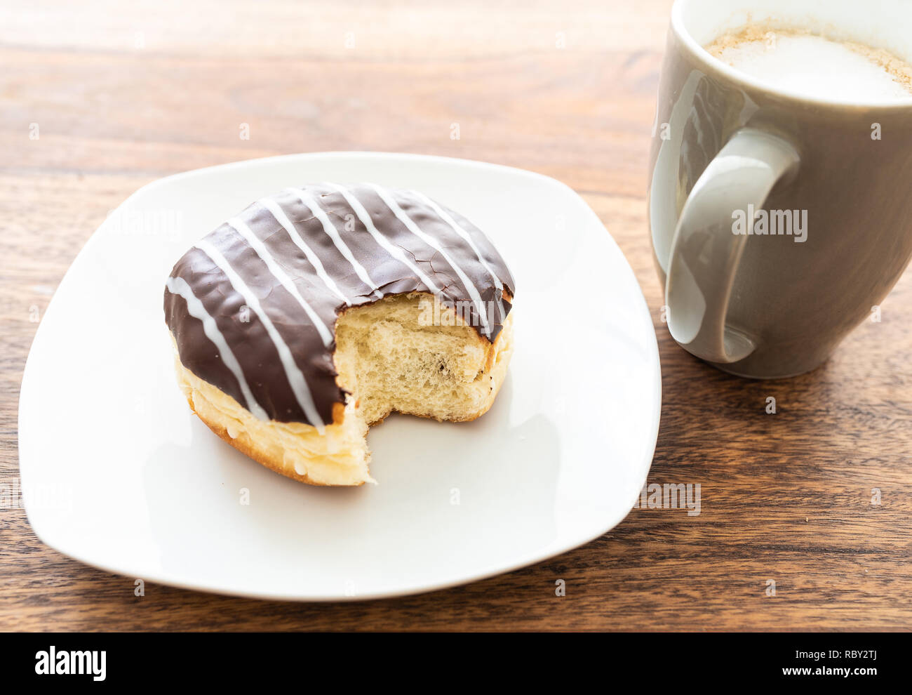 high angle view of chocolate coated jelly doughnut on wooden table Stock Photo