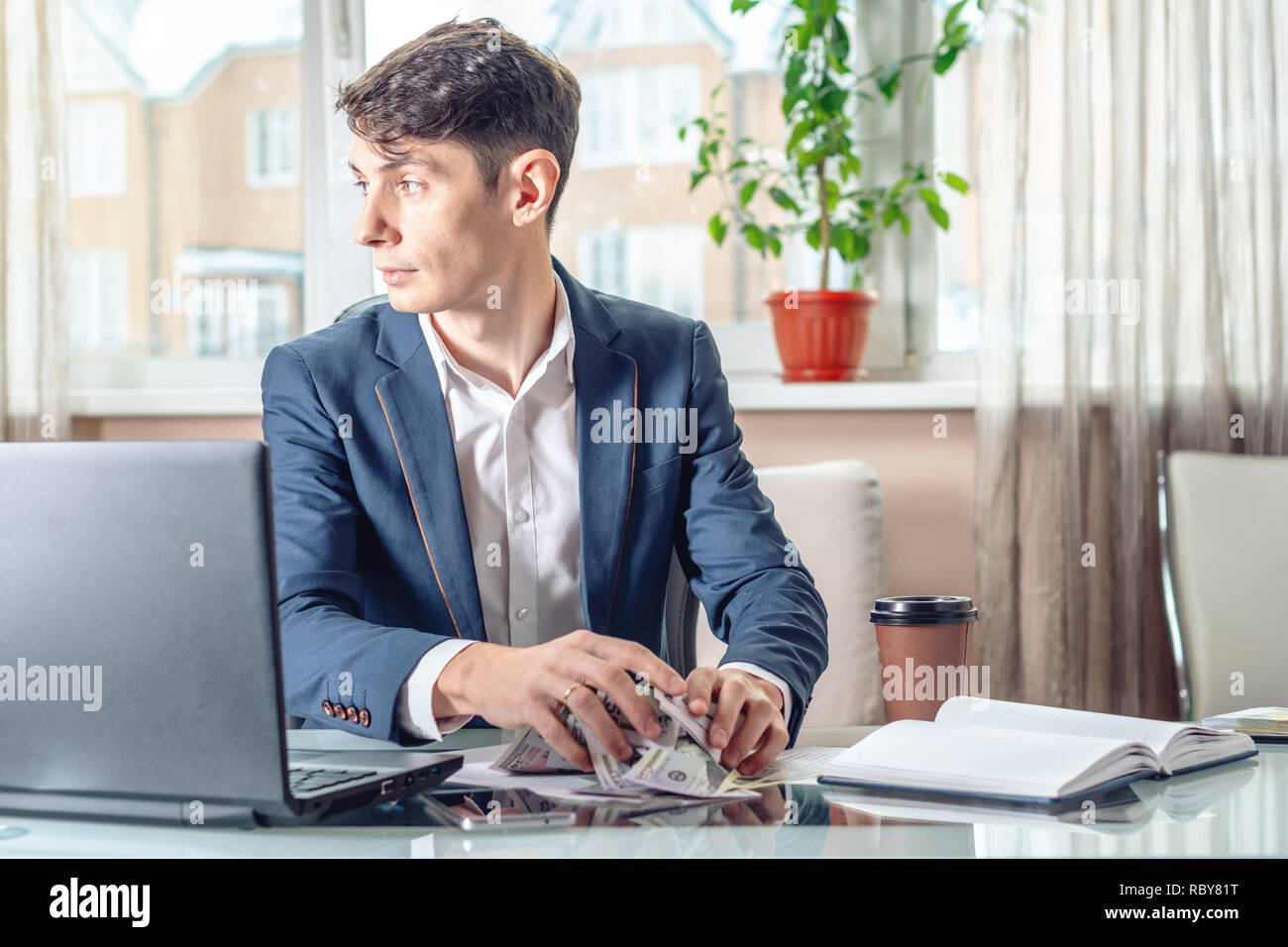 Businessman official sitting in the workplace in the office hides a bribe unnoticed in his pocket. The concept of corruption and bribery Stock Photo