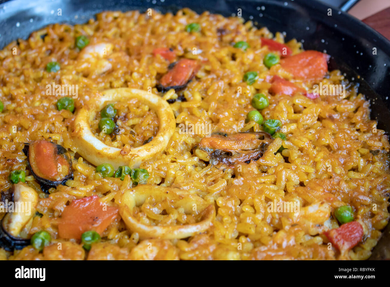 Fresh Spanish paella with rice and seafood in frying pan closeup Stock Photo