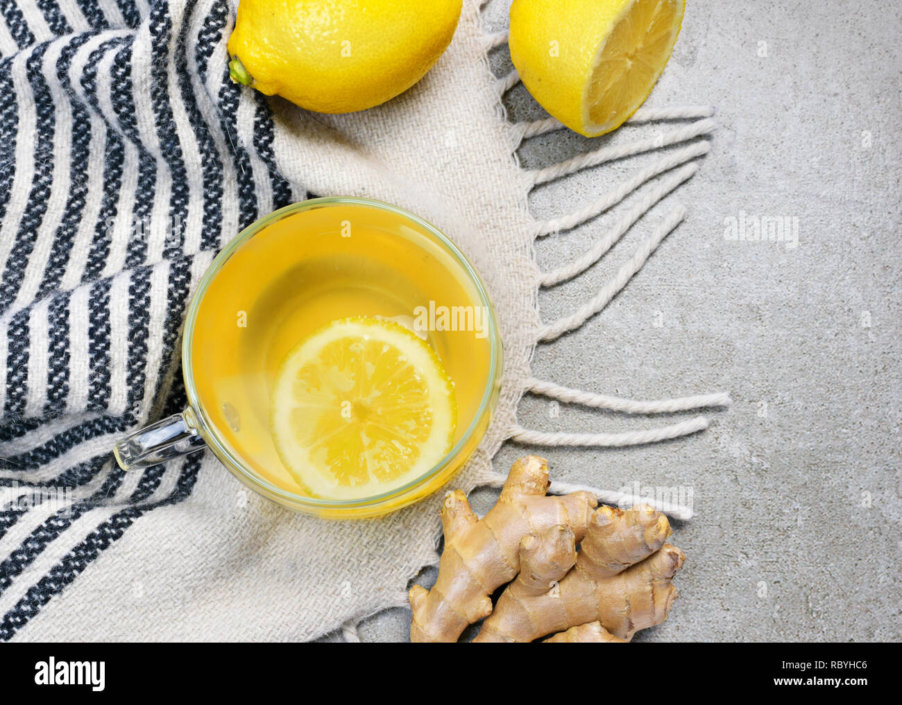 Ginger tea with lemon slice and glass cup. Healthy tea time with fresh ginger root. Winter scene, top view. Stock Photo