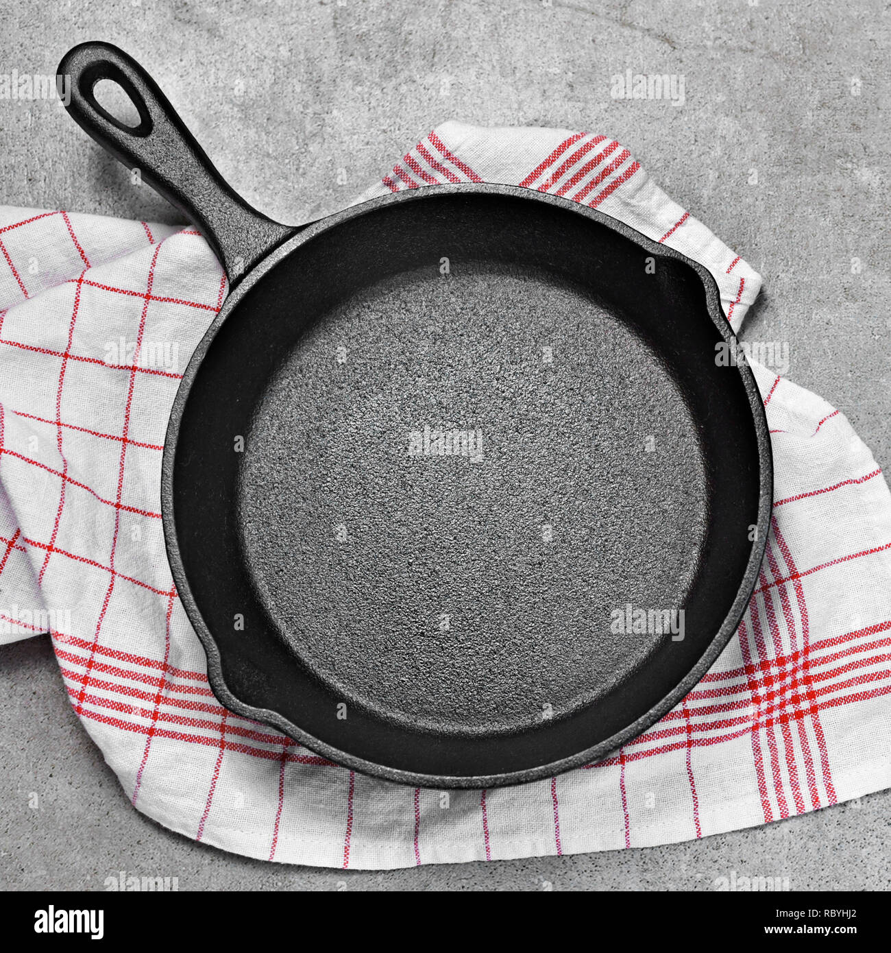Cast iron pan on a grunge concrete background with copy space. Empty iron pan, top view or high angle shot with herbs and tomatoes.Cast iron pan on a Stock Photo