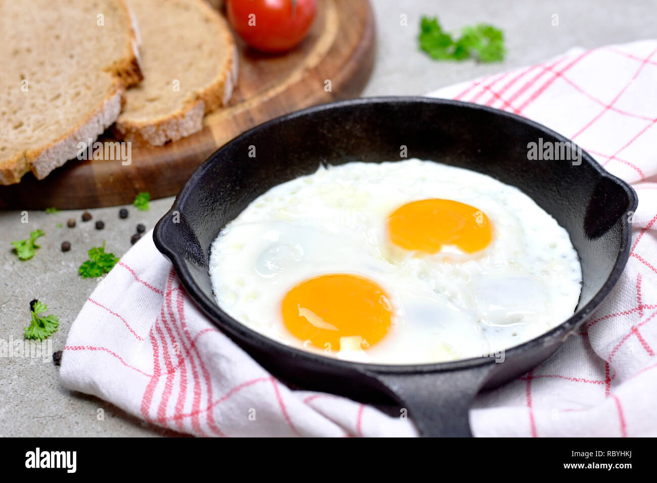 Delicious fried eggs in a cast iron pan. Top view of eggs and bread