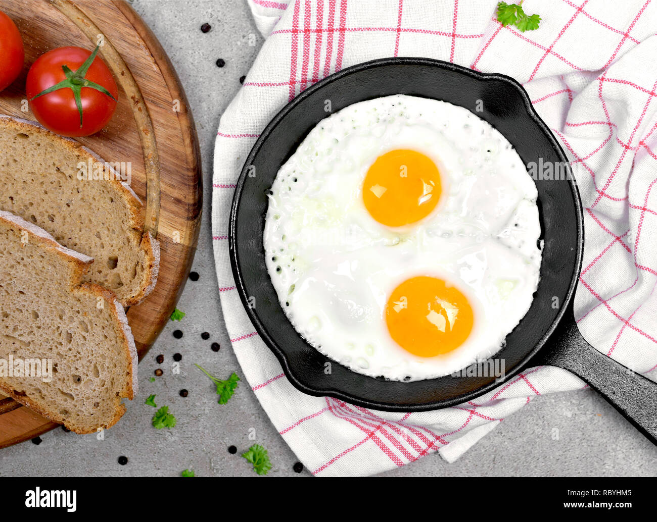 Delicious fried eggs in a cast iron pan. Top view of eggs and bread