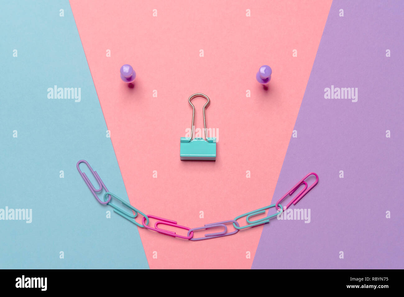Office objects arranged in the form of a smiley on a colorful paper background. Flat lay image in the minimalist style Stock Photo