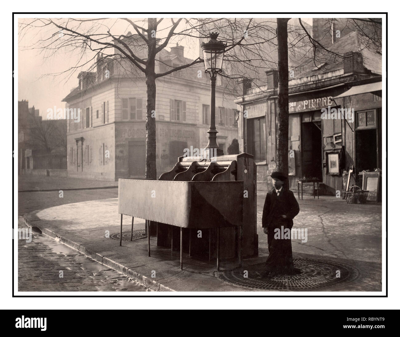 Vintage B&W French 'Pissoir' 'Uritrottoir' typical historical Paris Street Men’s Urinal Cast iron and slate urinal with three stalls raised modesty screen, mounted with lamppost and lantern.With young man standing nearby. Avenue du Maine, Paris, France. Date circa 1865  Charles Marville photographer  (1813–1879) Stock Photo