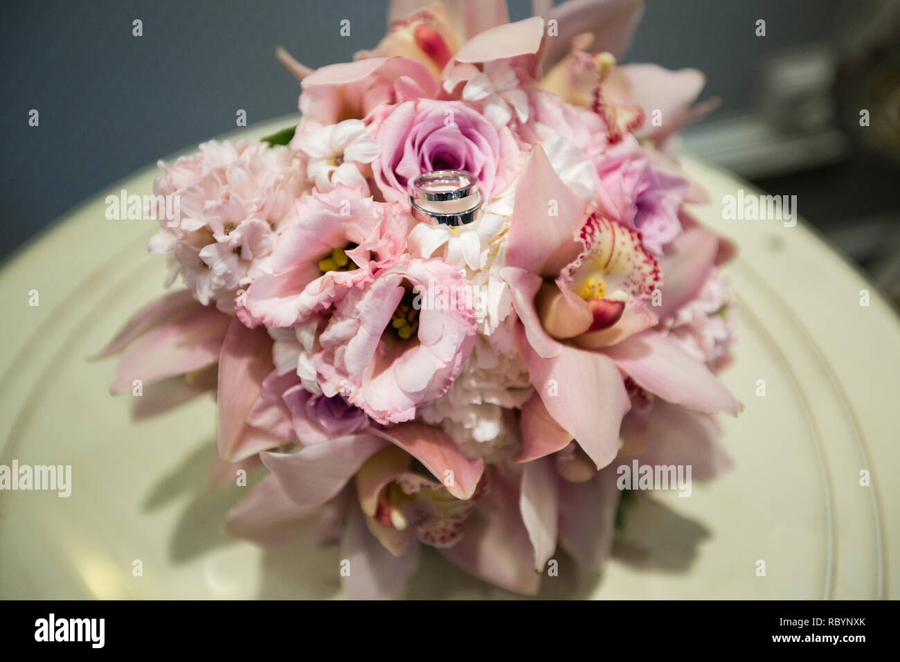 A pair of wedding gold rings on a bouquet of pink flowers, close up shot Stock Photo