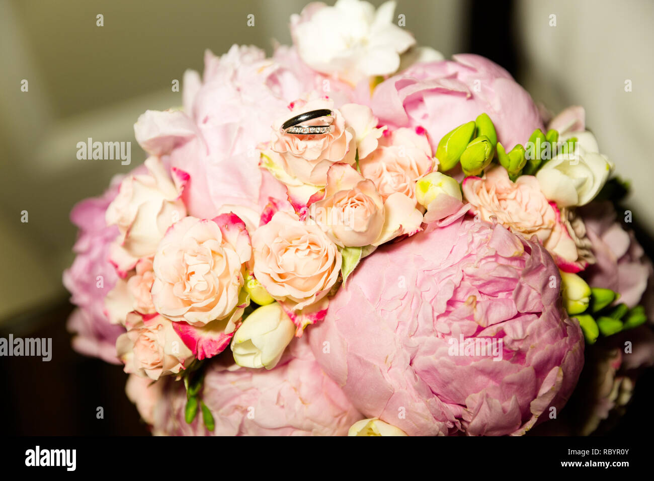 A pair of wedding gold rings on a bouquet of pink flowers, close up shot Stock Photo