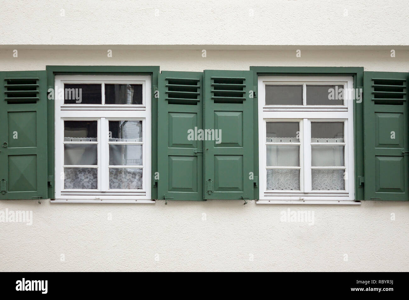 Old ancient wooden window with blinds or shutters. Scenic original and colorful view of antique windows in old city Sindelfingen, Germany. Isolated on wall. No people. Front view. Old fashioned style. Stock Photo