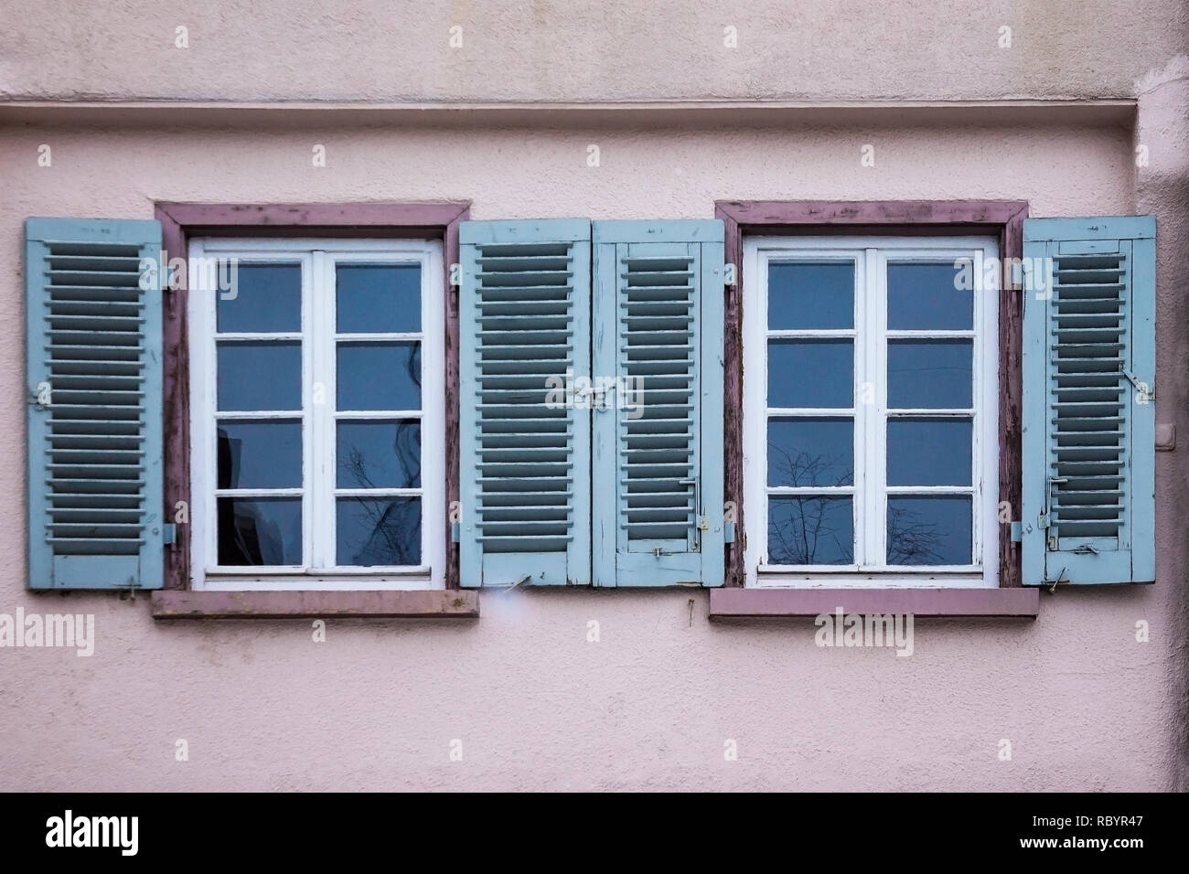Old ancient wooden window with blinds or shutters. Scenic original and colorful view of antique windows in old city Sindelfingen, Germany. Isolated on wall. No people. Front view. Old fashioned style. Stock Photo
