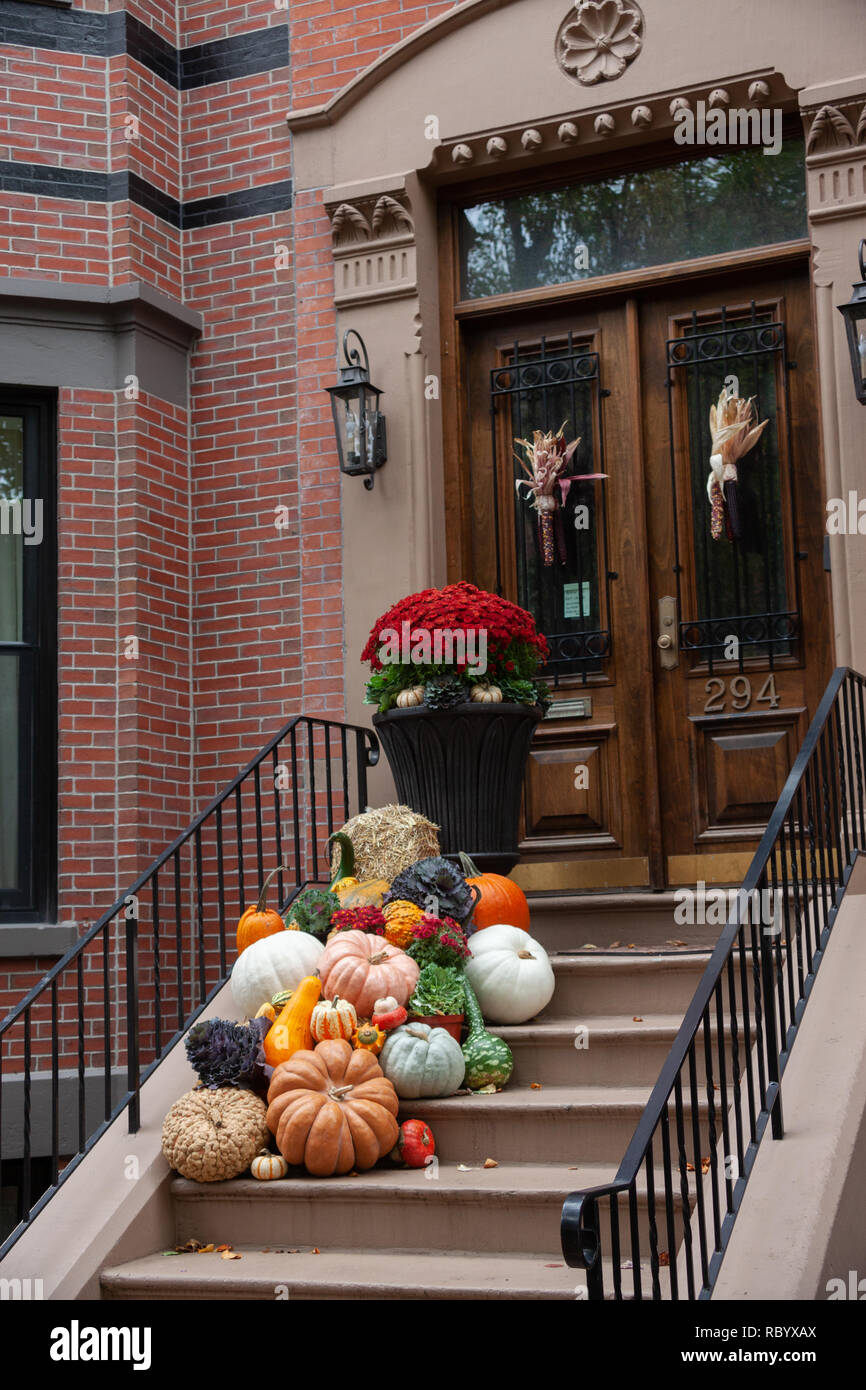 A display of pumpkins and gourds on the steps of a brownstone house on ...