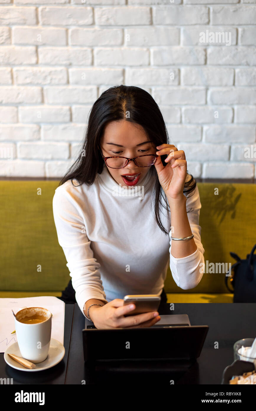 Girl using phone while working in a coffee bar Stock Photo - Alamy