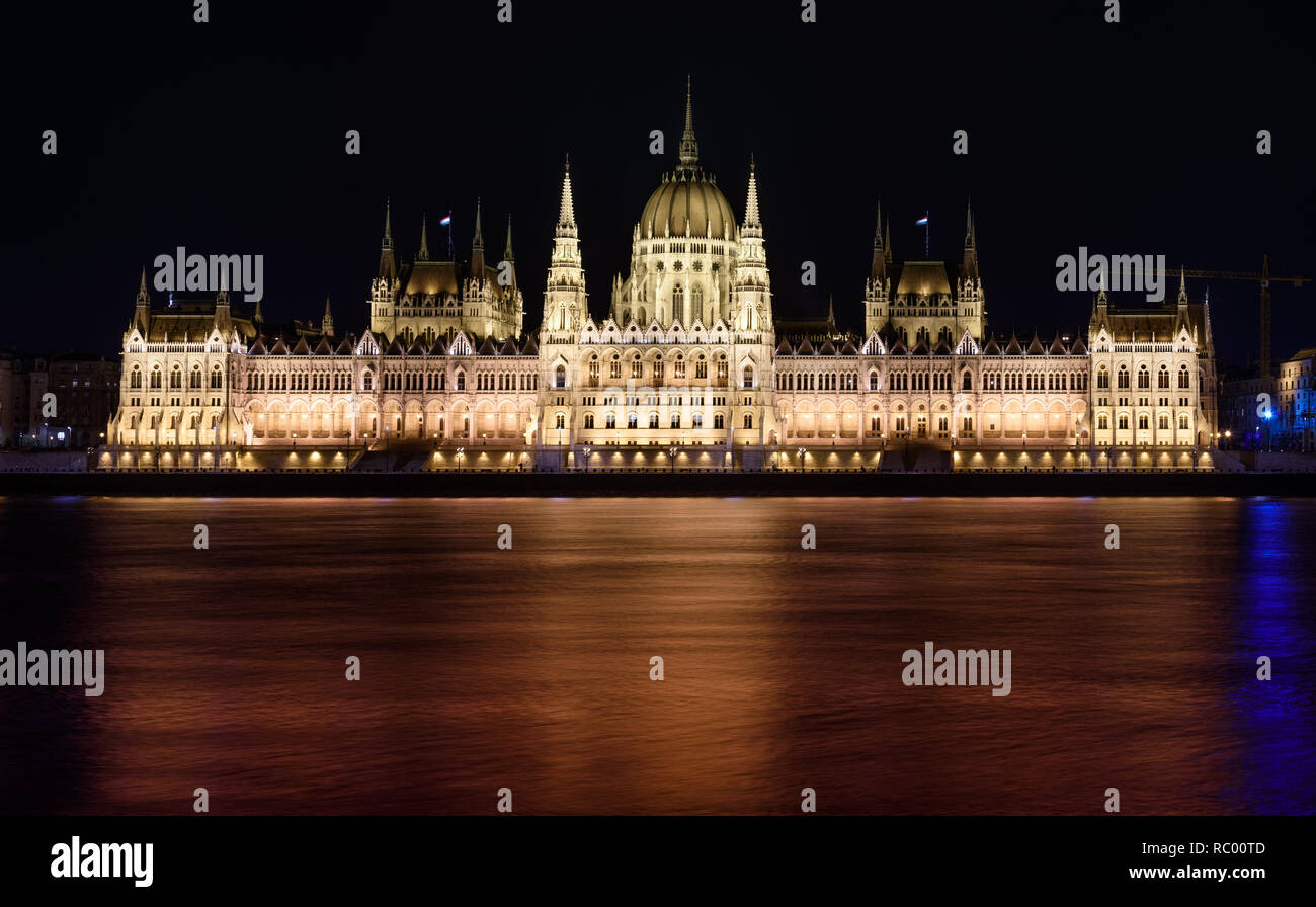 Hungarian Parliament building, in Budapest, at night. The building is lit up, and the Danube is flowing smoothly in front of it. Stock Photo