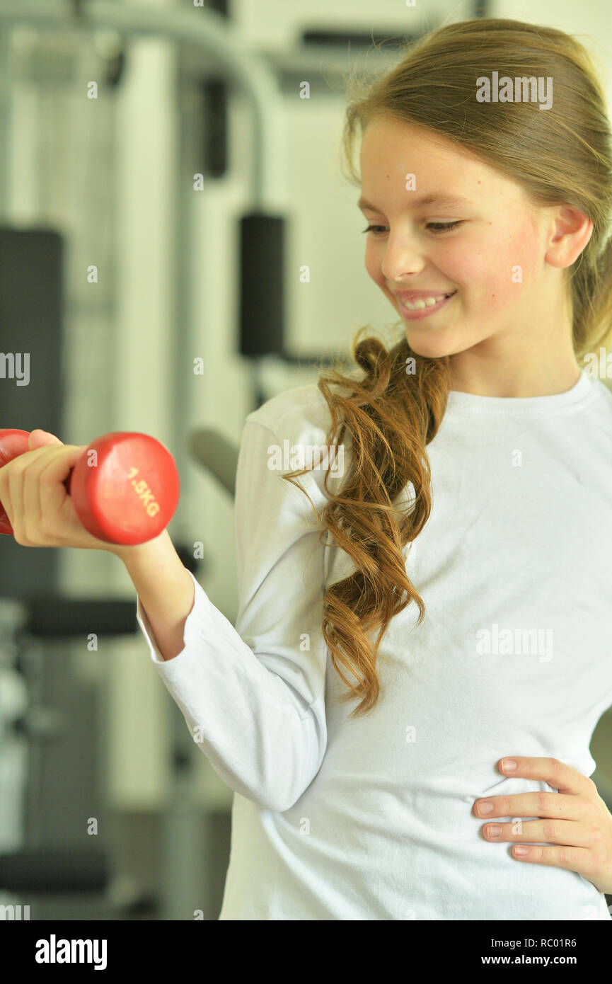 Portrait of little girl doing exercises with dumbbell in gym Stock ...