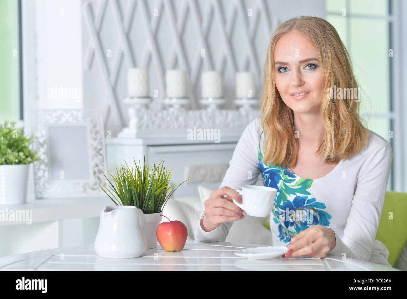 Beautiful blonde young woman drinking tea at kitchen Stock Photo