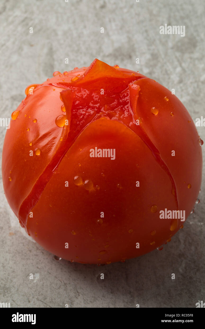 Start of peeling a single fresh tomato Stock Photo