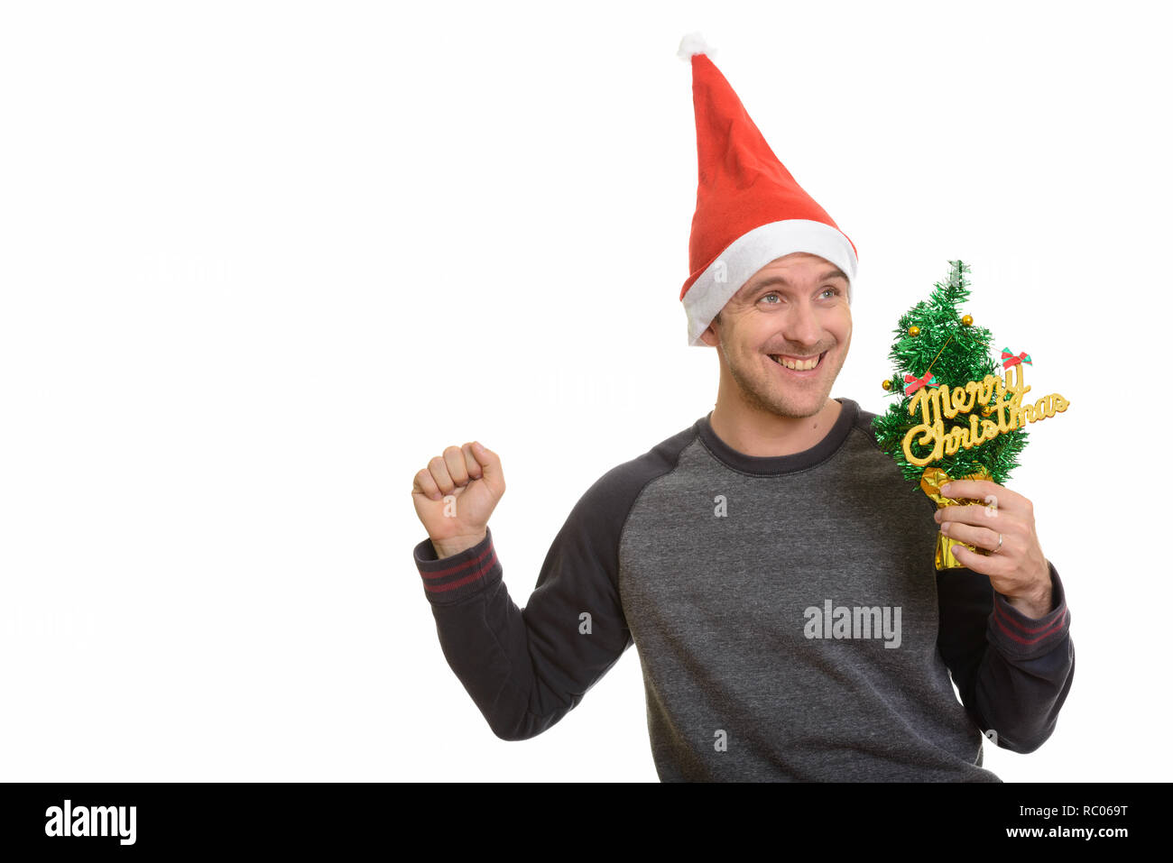 Happy Caucasian man holding Merry Christmas tree looking excited Stock Photo