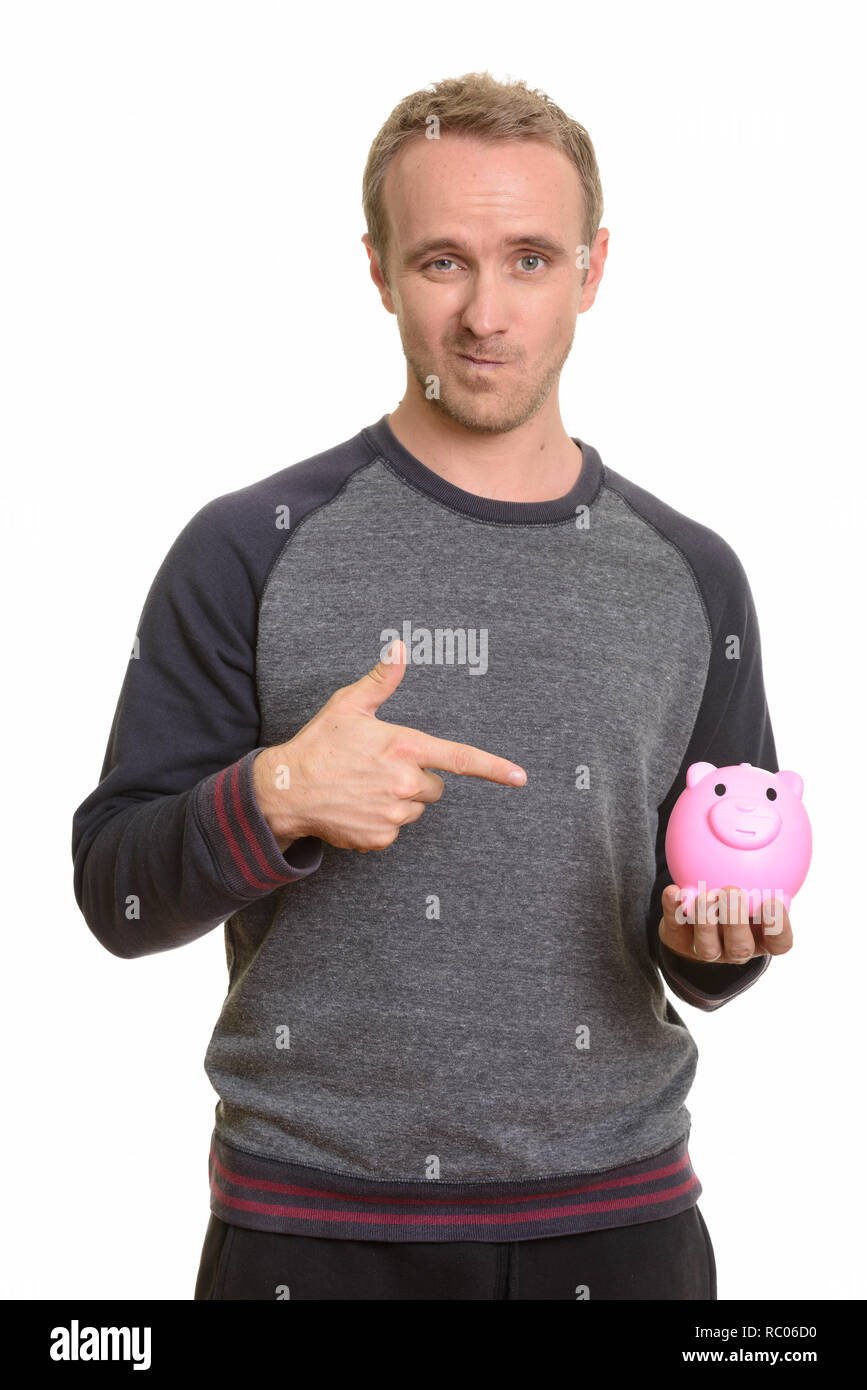 Handsome Caucasian man holding piggy bank and pointing finger lo Stock Photo