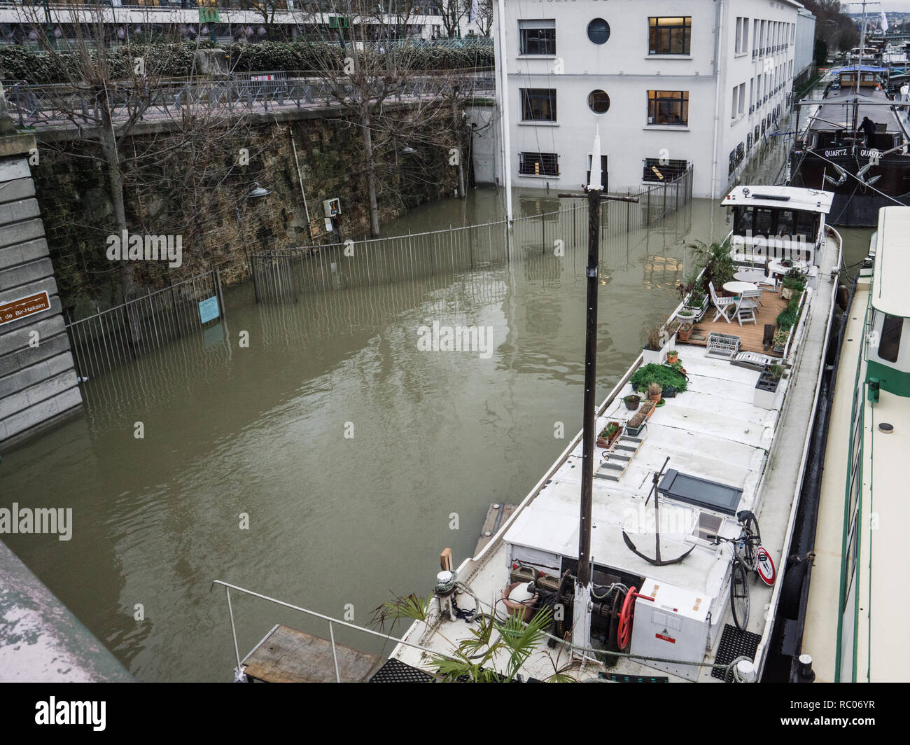 PARIS, FRANCE - JAN 30, 2018: Port Autonome de Paris building covered with water and nearby peniche barge after Swollen river Seine river's embankments overflow after days of heavy rain Stock Photo