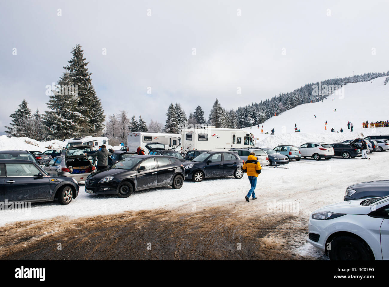 MUMMELSEE, GERMANY - FEB 18, 2018: Winter day with snow and ski slope seen from parking area with kids, parents having fun in German mountains Stock Photo