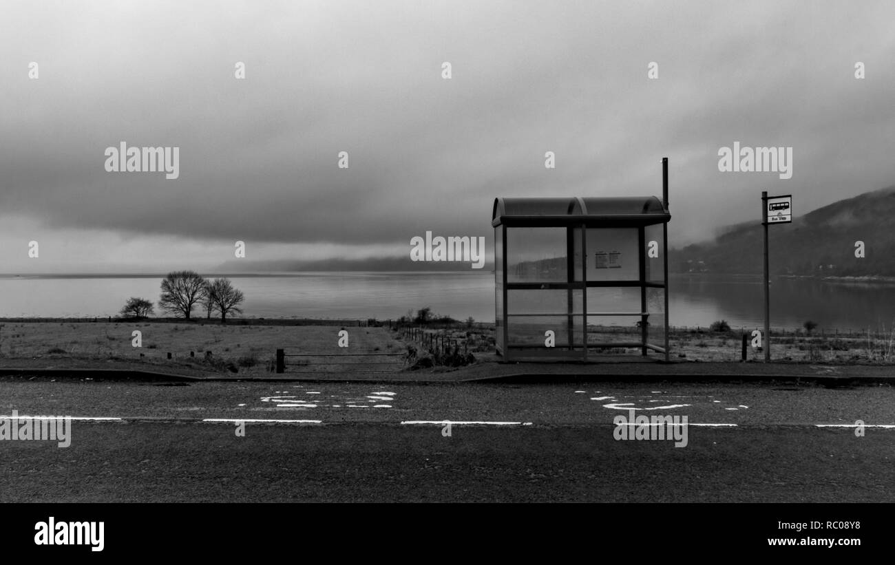 Black and white picture of the bus stop in country side area up North in Scotland near Fort William. Empty road and lake on the background Stock Photo