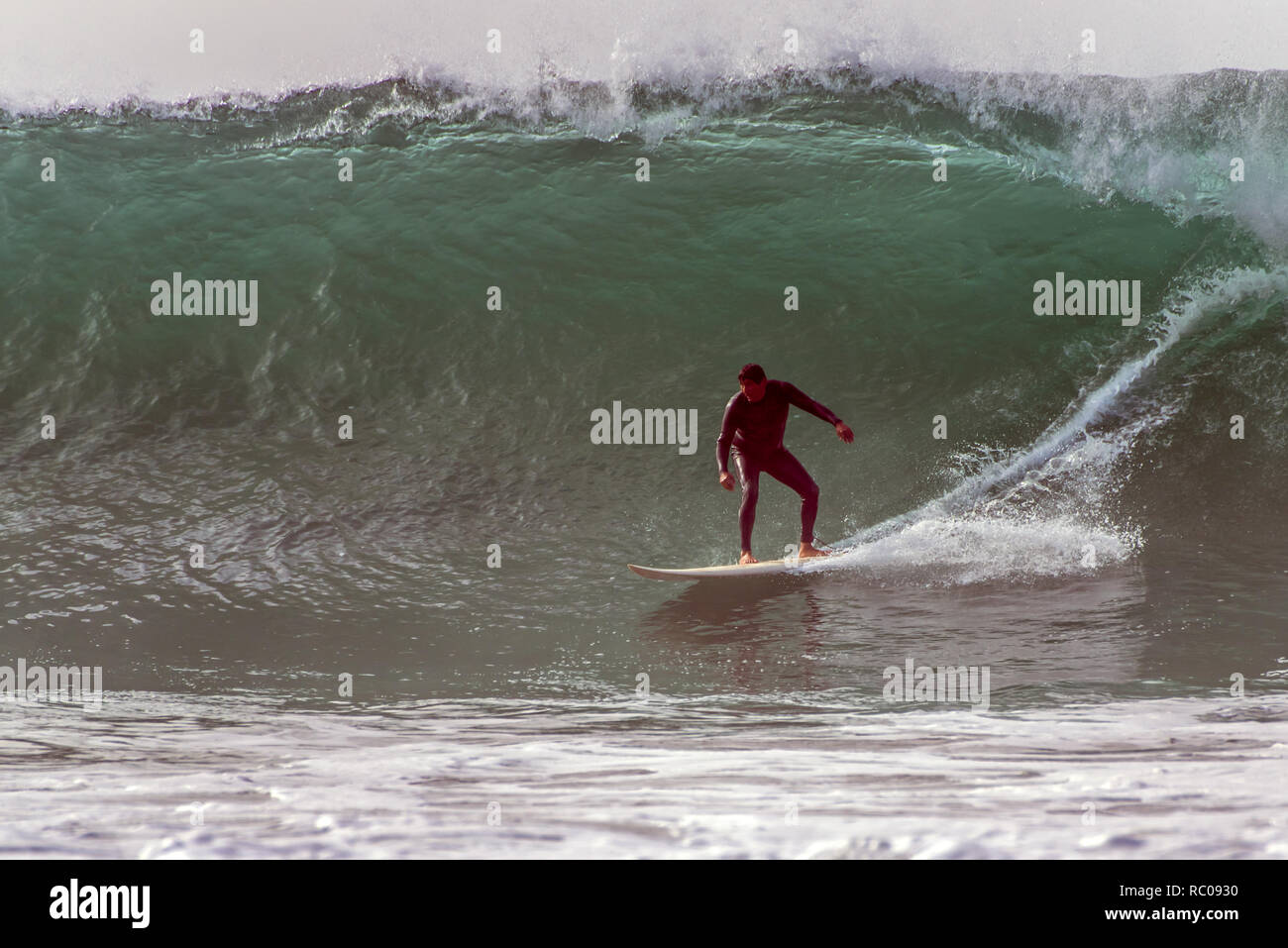 Goofy Foot Surfer In Black Wetsuit Dropping Into Barrel Of Goofy Foot Surfer In Black Wetsuit Dropping Into Barrel Of
