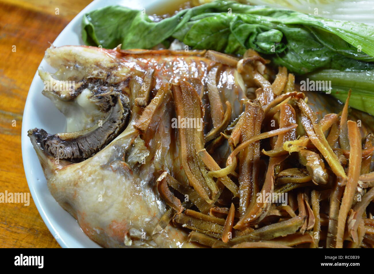steamed red mango fish with vegetable topping slice ginger on plate ...