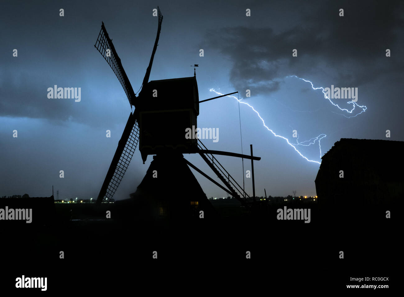 Windmill silhouette with powerful lightning bolts streaking through the sky during a severe thunderstorm in Holland. Stock Photo