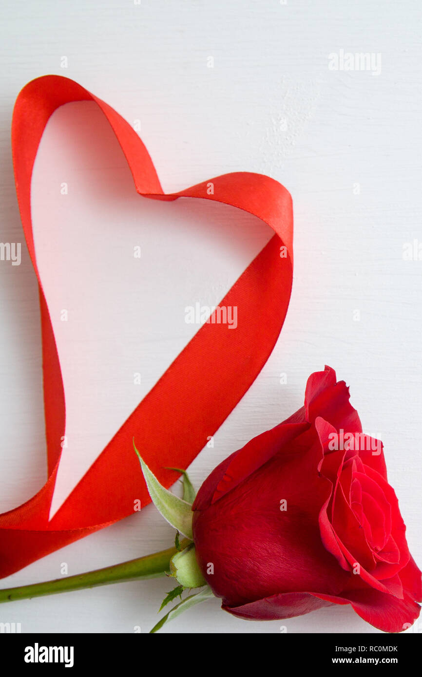 Heart shape made of red ribbon with red rose on white wooden Background ...