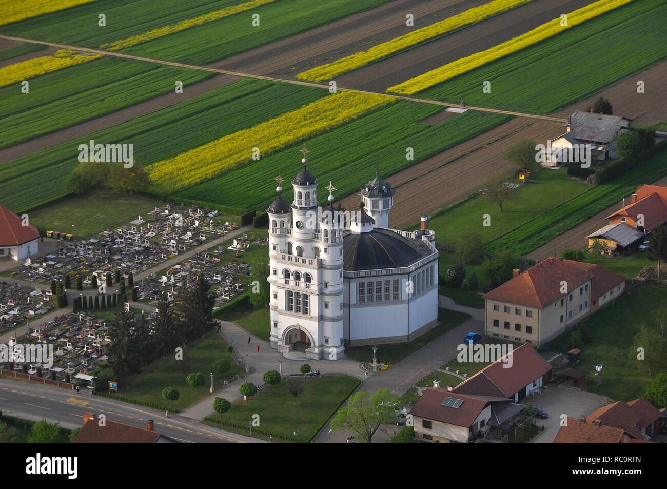 Aerial view of Holy Trinity Church in a small European village in sunset, a cemetery next to the church, unique architecture, Odranci, Slovenia Stock Photo