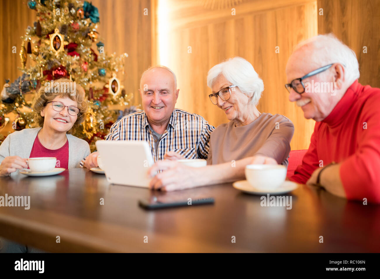 Jolly senior friends using gadget in cafe Stock Photo