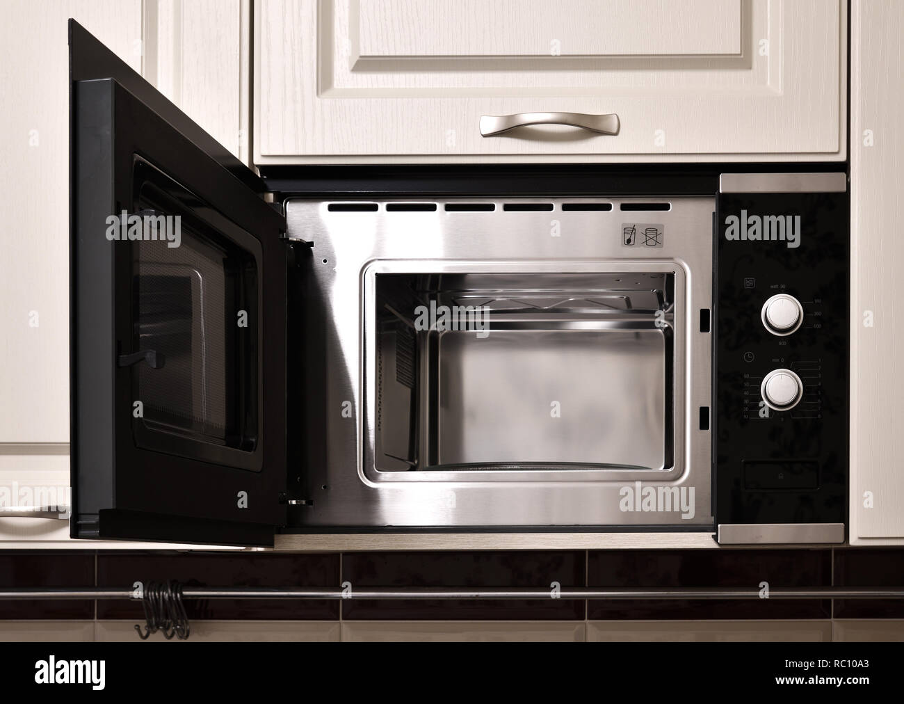 Open empty microwave in the kitchen cupboard Stock Photo