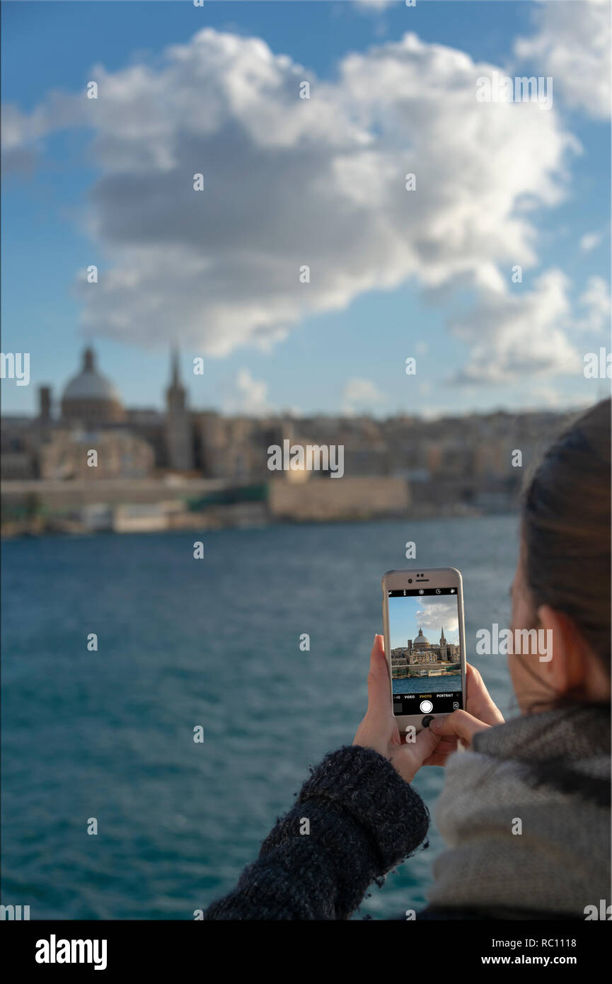 woman tourist taking a photo on her iphone of Valletta in Malta. Stock Photo