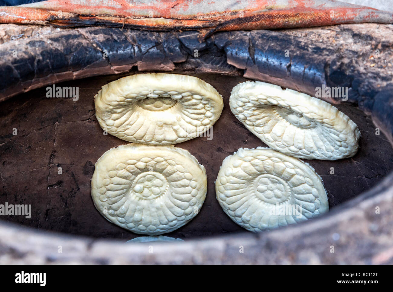 Traditional Uzbek flatbread baking in the tandir oven Stock Photo