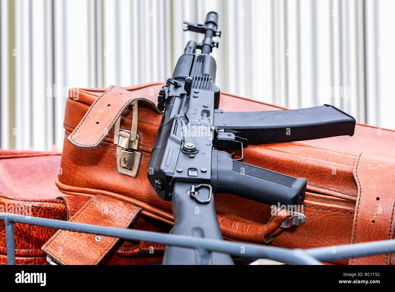 Kalashnikov ak-47 and vintage leather travel suitcases Stock Photo