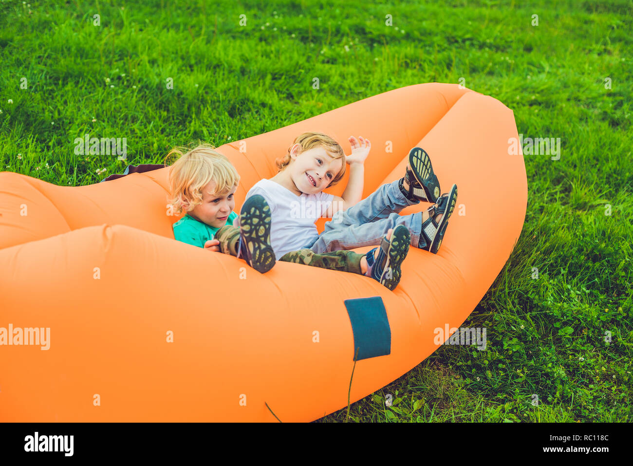 Two cute boys resting on an air sofa in the park.. lamzac Stock Photo