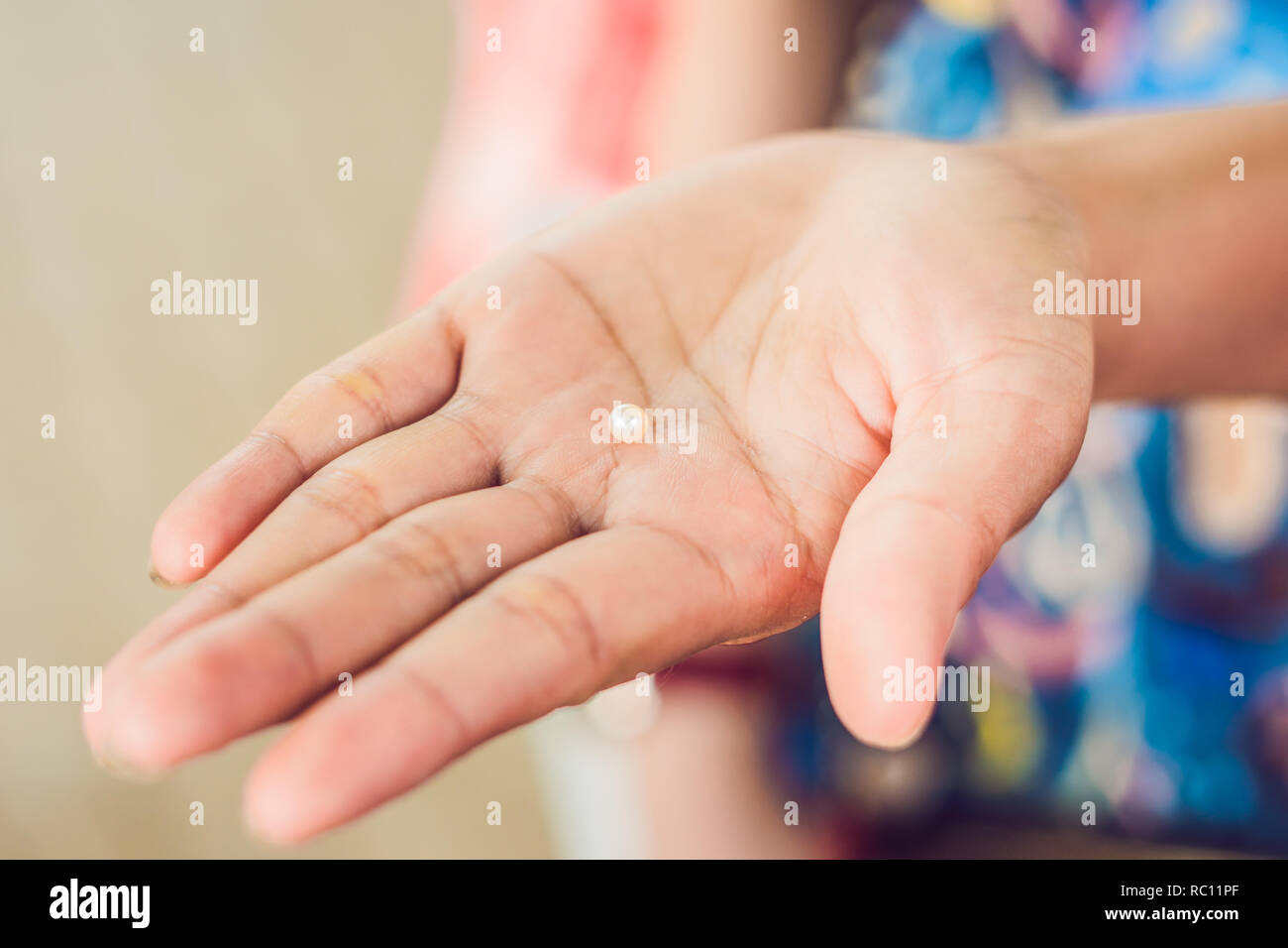 Hand with tweezers holding pearl and oyster on wooden background. Stock Photo