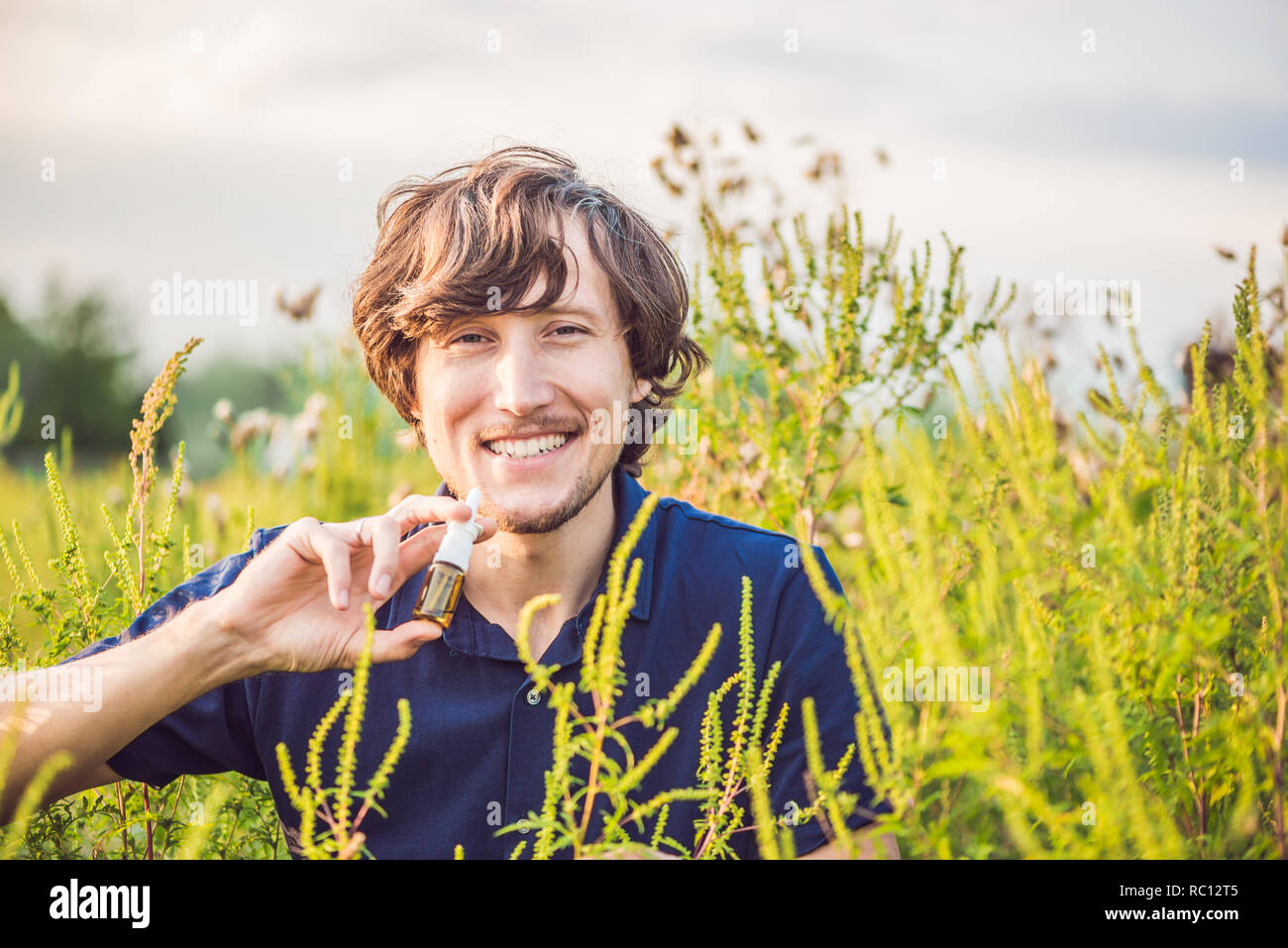 Young man uses a spray from an allergy because of an allergy to ragweed. Stock Photo