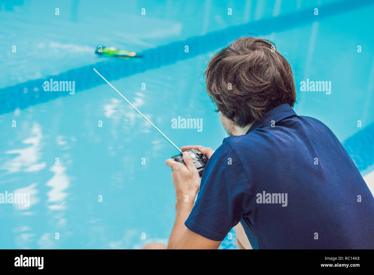 Man playing with a remote controlled boat in the pool Stock Photo
