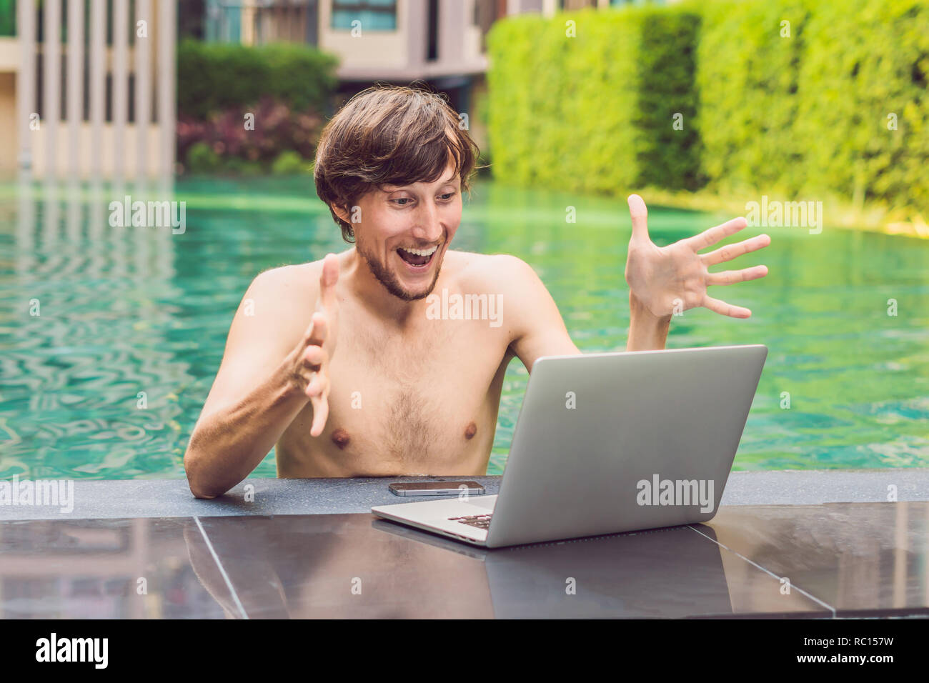 Young freelancer working on vacation next to the swimming pool Stock Photo