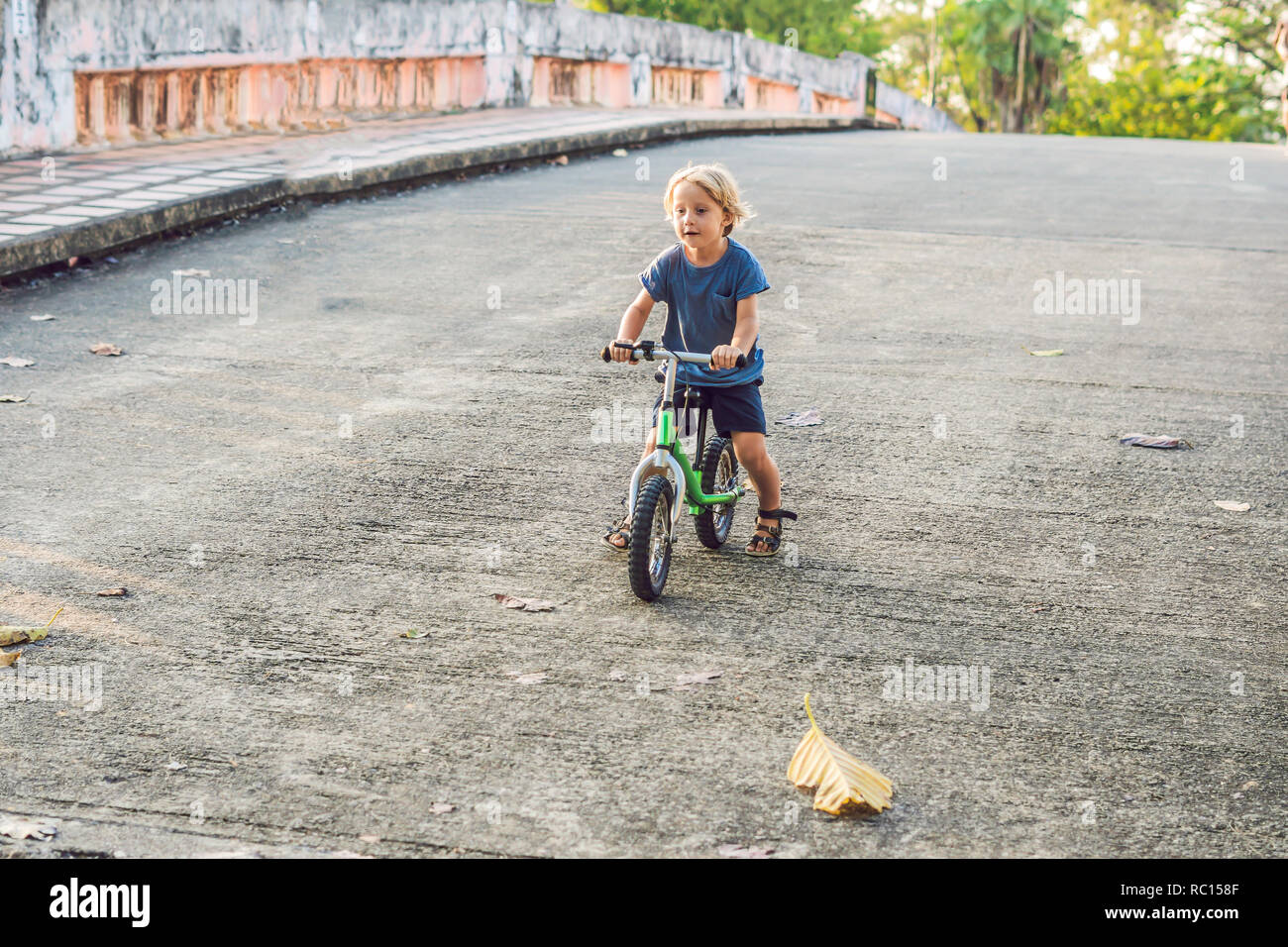 Little boy on a bicycle. Caught in motion, on a driveway motion blurred. Preschool child's first day on the bike. The joy of movement. Little athlete learns to keep balance while riding a bicycle Stock Photo
