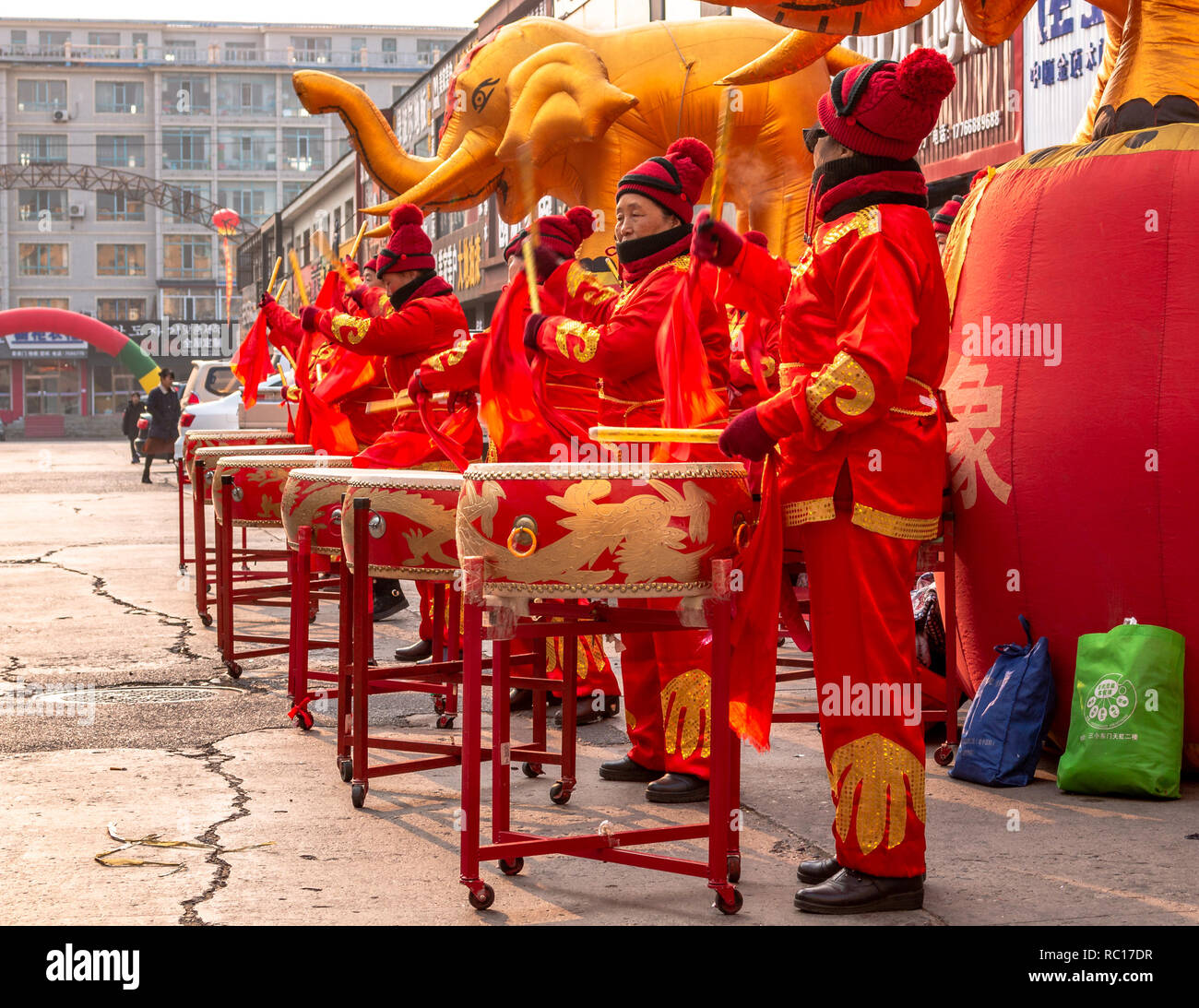 Women in red golden outfits drumming during the ceremonial of the opening of a store in Hunchun city of China, Jilin Province in the Yanbian Prefecture Stock Photo