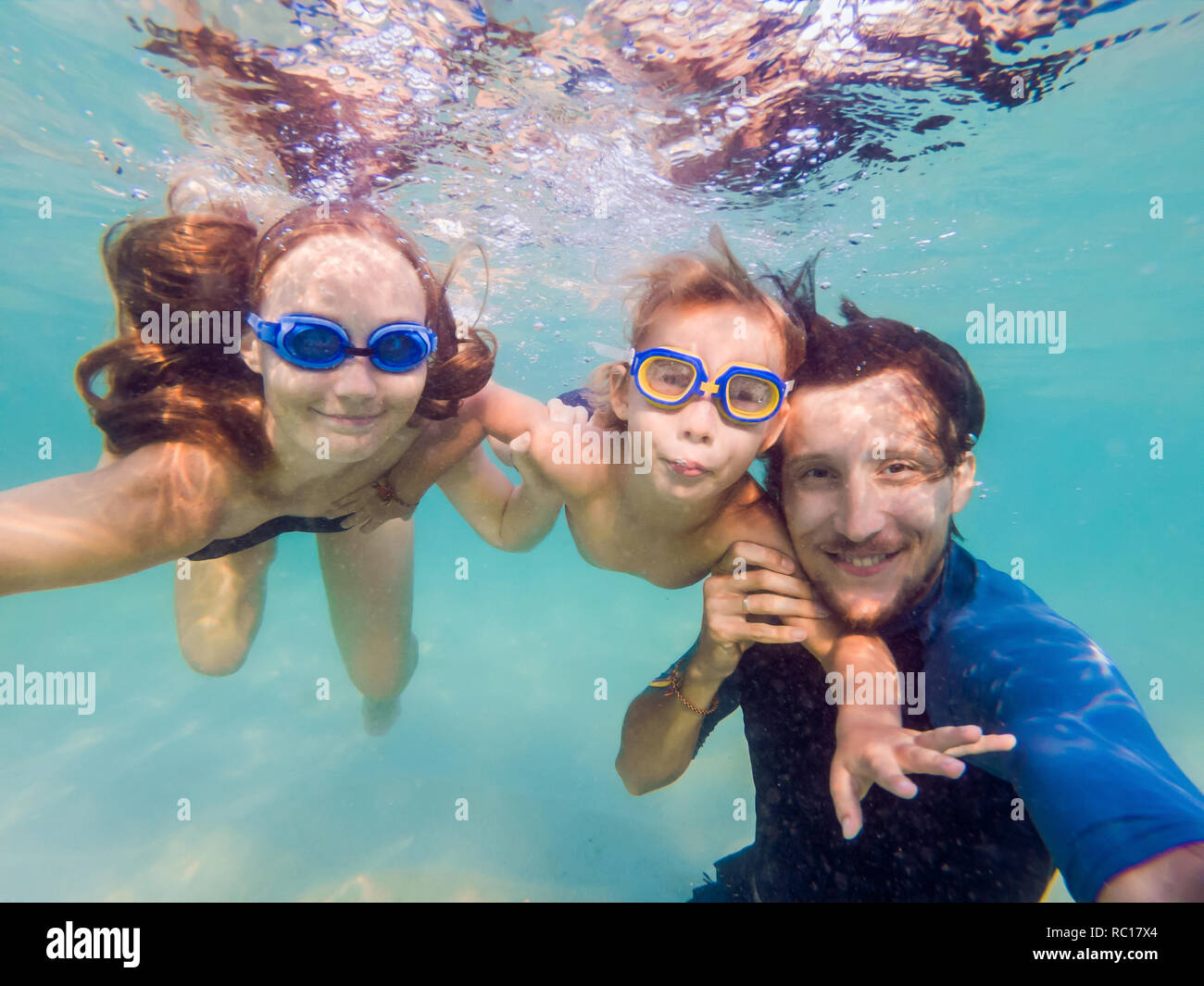 Family fitness mother, father, baby son learn to swim together, dive underwater with fun in