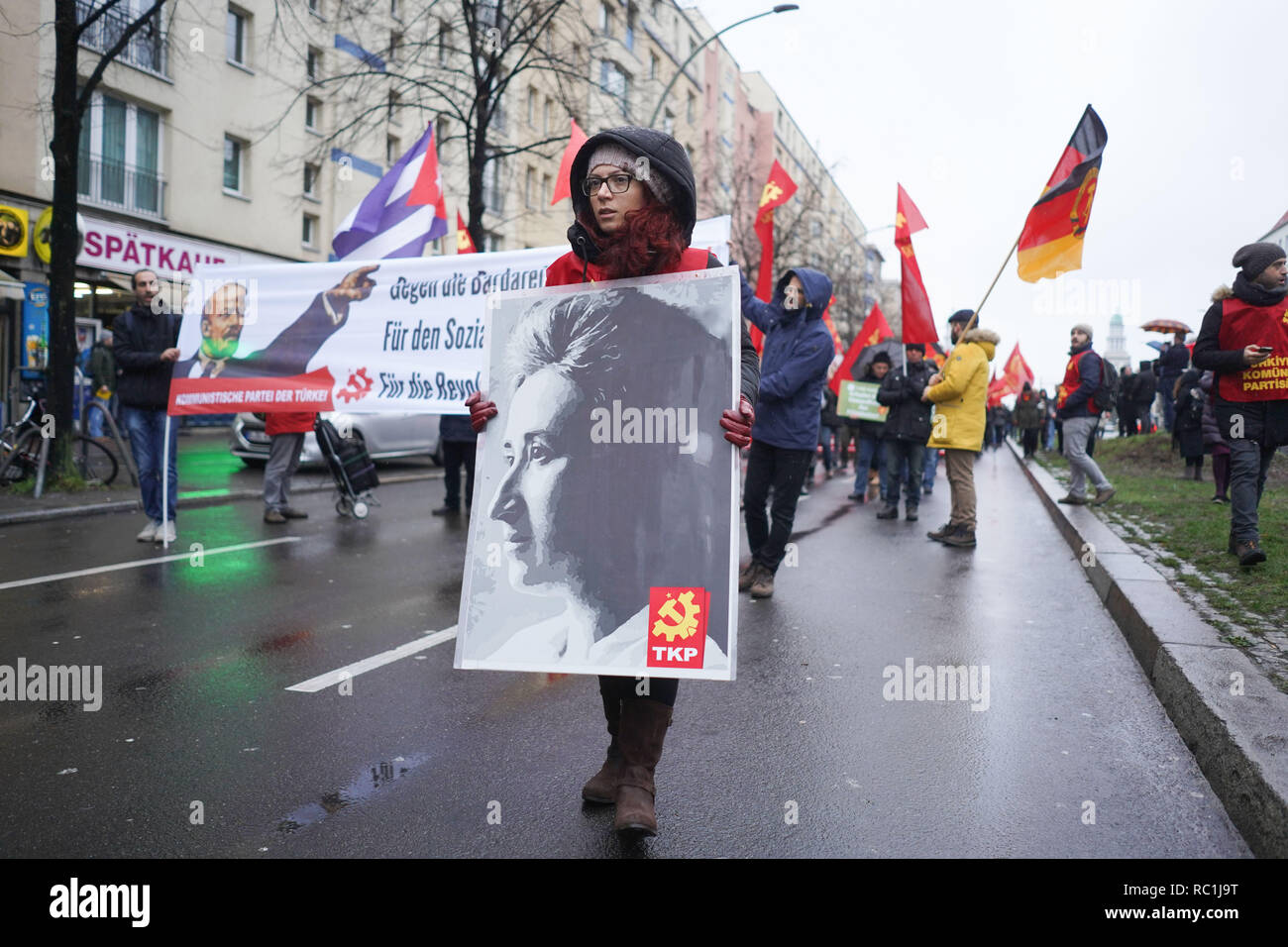 Berlin, Germany. 13th Jan, 2019. A young woman on Karl-Marx-Allee carries a  photograph of the Communist leader Rosa Luxemburg on a demonstration in  memory of the Communist leaders Rosa Luxemburg and Karl