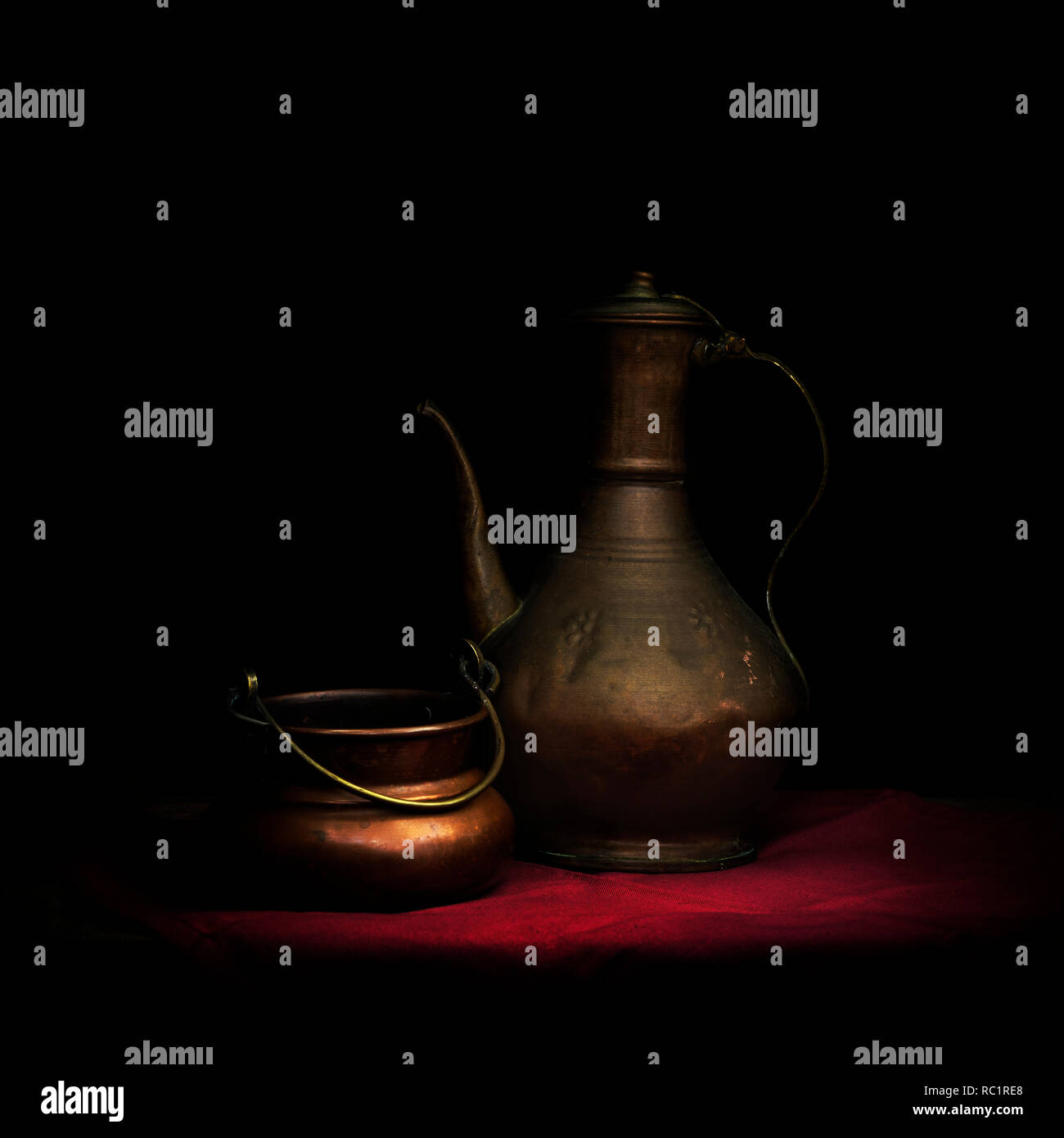 Copperware. Teapot or coffee pot or kettle...maybe MIddle Eastern. On red cloth with bowl. Stock Photo