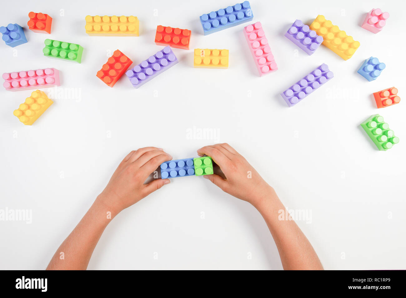 Kid hands play with colorful plastic construction blocks on white ...